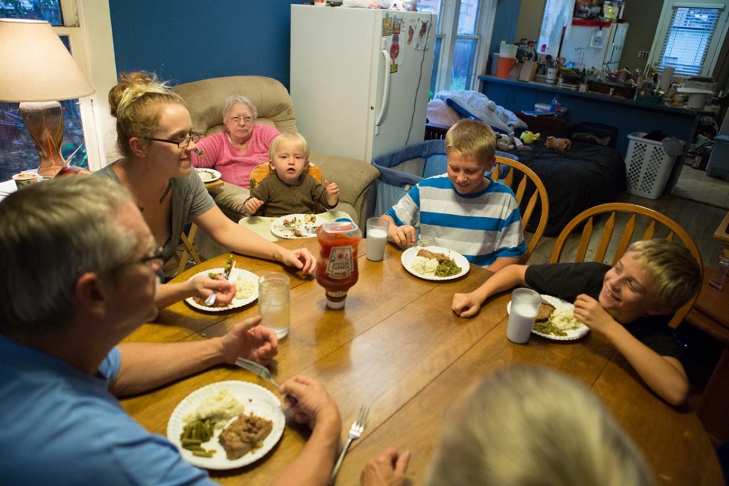 Family eating food around kitchen table