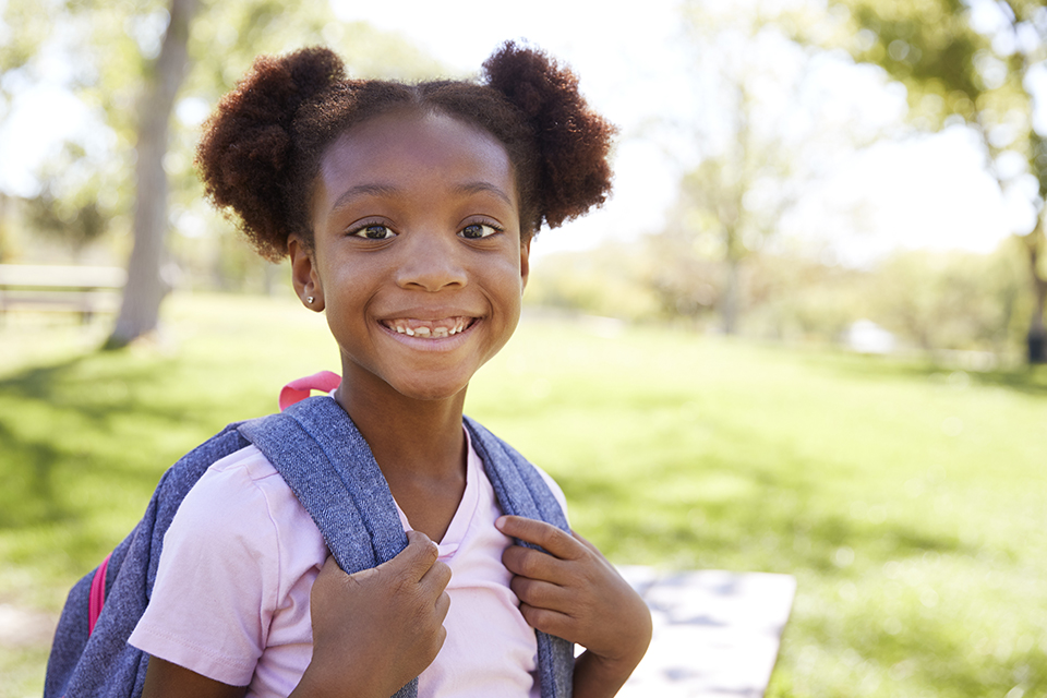 Girl smiling holding her backpack straps