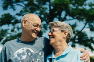 A senior man smiles at his wife, his arm around her shoulder