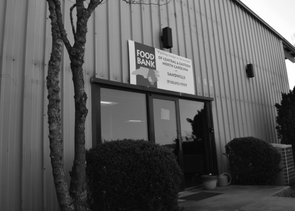 Exterior of Sandhills Branch. Black & white photo of paneled building with white sign reading Food Bank