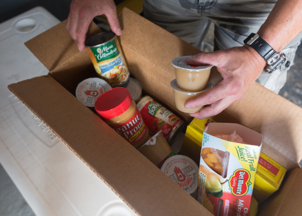 Box filled with non-perishables including soup, apple sauce, and peanut butter