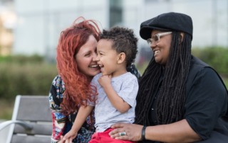 Two women laughing with their child