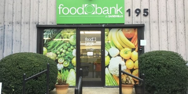 Exterior of Sandhills Branch. Paneled building with green sign reading Food Bank at Sandhills