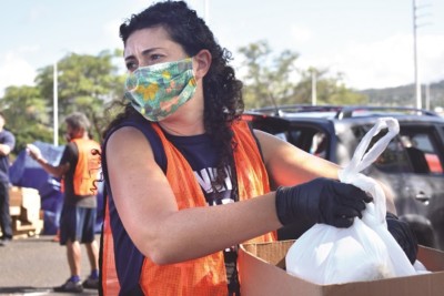 Masked volunteer holds a box with a bag of food in it