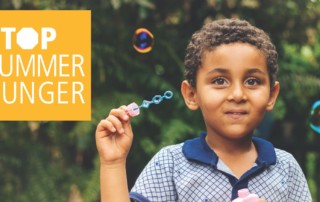 Little boy smiles holding a bubble wand surrounded by bubbles next to words - "Stop Summer Hunger"