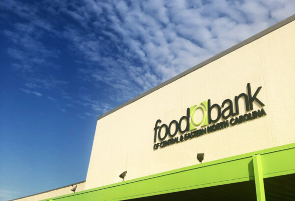 Exterior of Raleigh Branch. White, stone building with bright green portico and matching lettering. Food Bank of Central & Eastern North Carolina